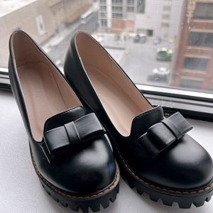 High heeled loafers with lug sole.   Black with decorative bow.